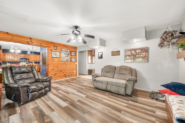 22251 210th Ave, Tustin, MI 49688 - living room with light wood-style flooring, ceiling fan, baseboards, and wooden walls
