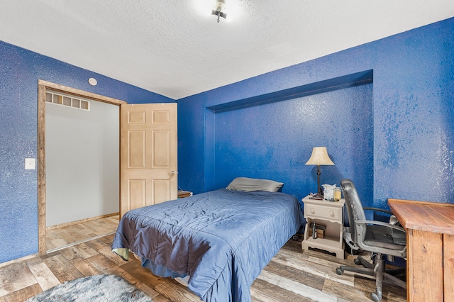 22251 210th Ave, Tustin, MI 49688 - bedroom with a textured wall, wood finished floors, a textured ceiling, vaulted ceiling, and an office area