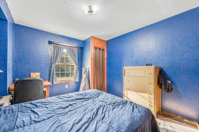 22251 210th Ave, Tustin, MI 49688 - bedroom with a textured wall, a textured ceiling, and wood finished floors