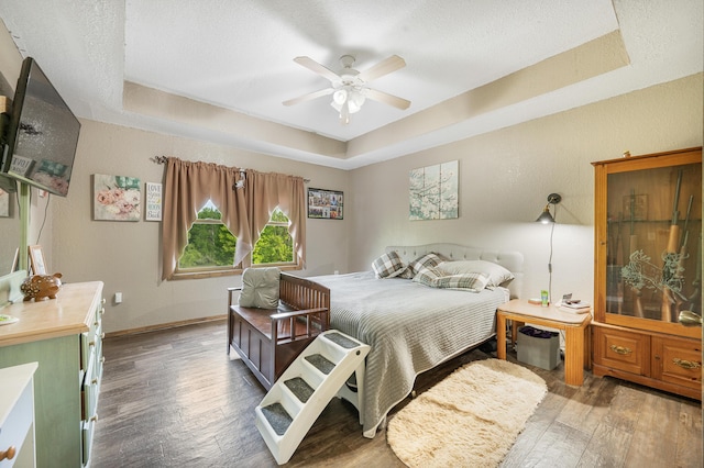 22251 210th Ave, Tustin, MI 49688 - bedroom with a tray ceiling, wood finished floors, baseboards, a textured ceiling, and ceiling fan