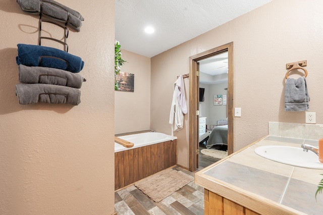 22251 210th Ave, Tustin, MI 49688 - ensuite bathroom featuring a garden tub, a textured wall, vanity, and recessed lighting