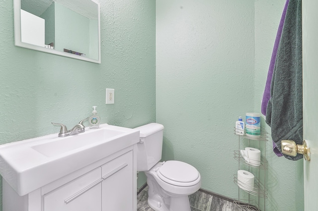 22251 210th Ave, Tustin, MI 49688 - bathroom featuring a textured wall, vanity, toilet, and baseboards