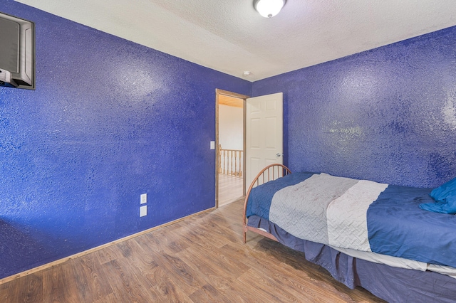 22251 210th Ave, Tustin, MI 49688 - bedroom with wood finished floors, a textured wall, and baseboards