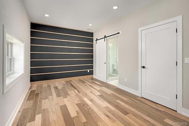 3634 Trumbull St Unit 65, Detroit, MI 48208 - unfurnished bedroom featuring a barn door, light wood-type flooring, recessed lighting, and baseboards