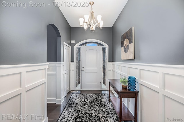 17769 Tiger Dr, Macomb, MI 48042 - doorway featuring a chandelier, dark wood finished floors, a decorative wall, a wainscoted wall, and arched walkways