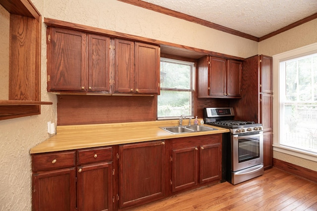 3804 Portage St, Kalamazoo, MI 49001 - kitchen with stainless steel gas stove, a textured wall, a textured ceiling, crown molding, and light wood finished floors