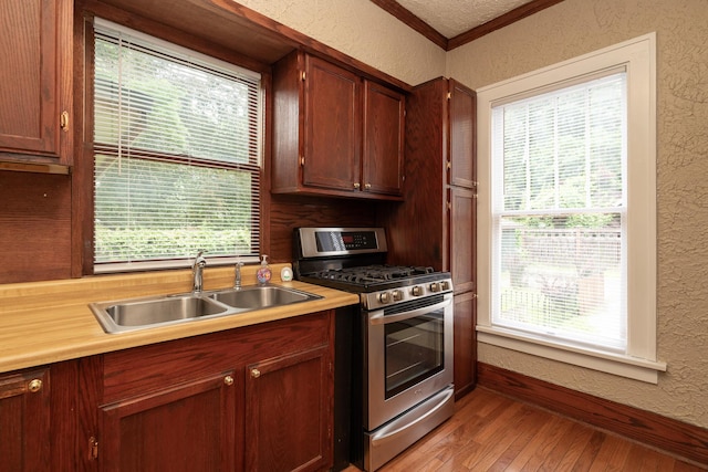 3804 Portage St, Kalamazoo, MI 49001 - kitchen featuring stainless steel range with gas cooktop, a textured wall, light wood finished floors, light countertops, and healthy amount of natural light