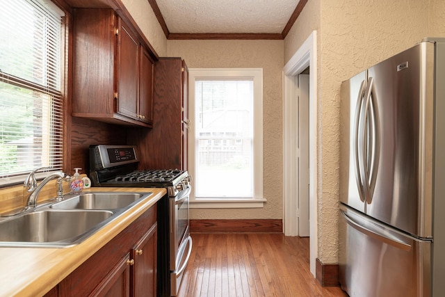 3804 Portage St, Kalamazoo, MI 49001 - kitchen featuring appliances with stainless steel finishes, a textured wall, light wood-style floors, light countertops, and crown molding