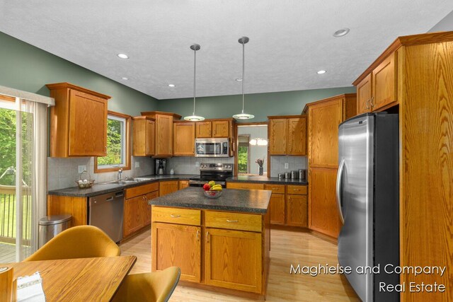 4349 Walter Rd, Wayland, MI 49348 - kitchen with appliances with stainless steel finishes, brown cabinets, dark countertops, a kitchen island, and recessed lighting