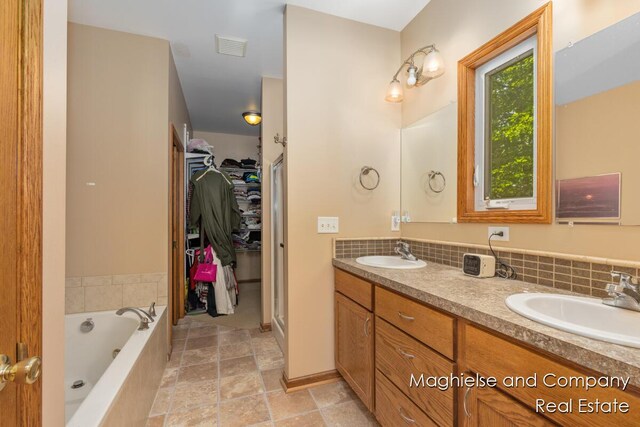 4349 Walter Rd, Wayland, MI 49348 - full bath with double vanity, a bath, a walk in closet, and decorative backsplash