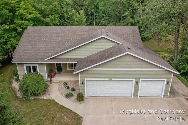 4349 Walter Rd, Wayland, MI 49348 - view of front facade featuring concrete driveway, a garage, roof with shingles, covered porch, and a view of trees