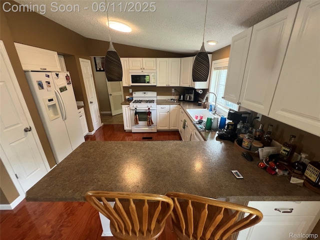 5550 Howe Rd, Grand Blanc, MI 48439 - kitchen featuring white appliances, a sink, a textured ceiling, vaulted ceiling, and a peninsula