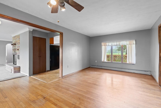 5244 Sand Creek Highway, Adrian, MI 49221 - unfurnished room featuring a baseboard radiator, wood-type flooring, a ceiling fan, arched walkways, and baseboards