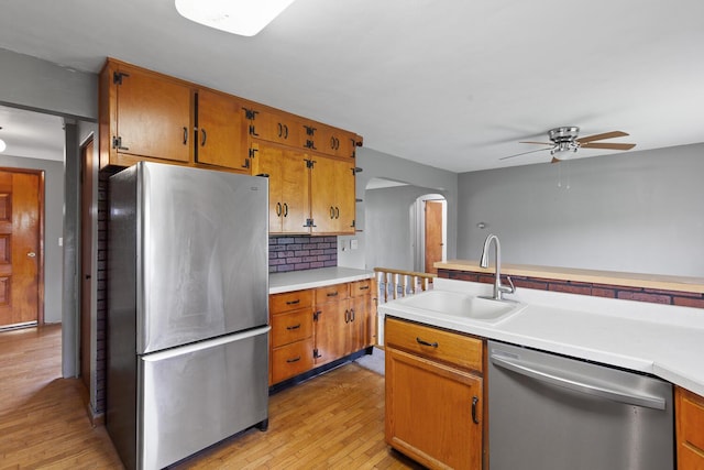 5244 Sand Creek Highway, Adrian, MI 49221 - kitchen featuring appliances with stainless steel finishes, a sink, ceiling fan, arched walkways, and light wood-style floors