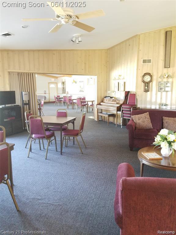 40859 Newport Dr, Plymouth, MI 48170 - dining area with carpet, wooden walls, and a ceiling fan