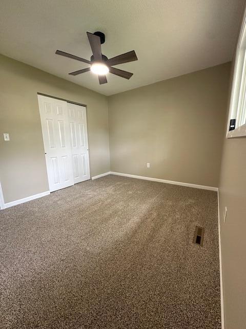 5511 Sunset Ct, Oscoda, MI 48750 - unfurnished bedroom featuring baseboards, a closet, carpet, and ceiling fan