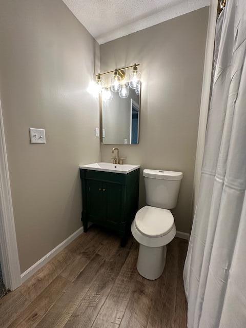 5511 Sunset Ct, Oscoda, MI 48750 - full bath featuring wood finished floors, vanity, a textured ceiling, baseboards, and toilet