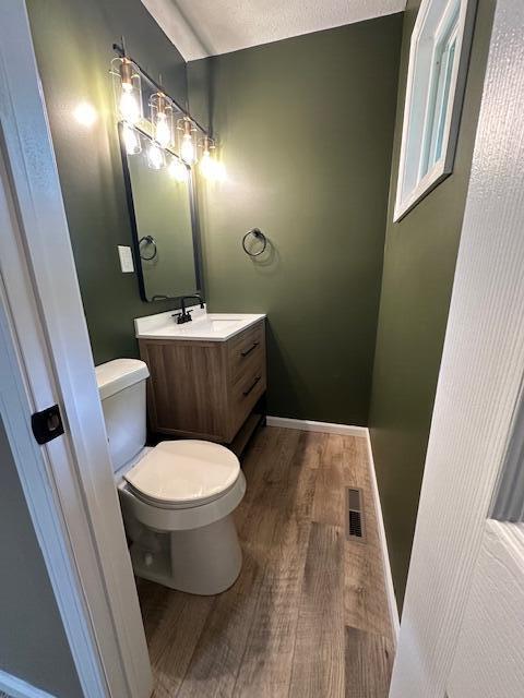 5511 Sunset Ct, Oscoda, MI 48750 - half bath featuring wood finished floors, toilet, and vanity