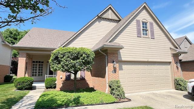 43573 E Perignon Dr N, Sterling Heights, MI 48314 - view of front of property with brick siding, a porch, concrete driveway, and a garage