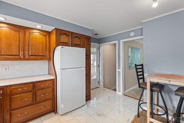 603 Outer Dr, Tecumseh, MI 49286 - kitchen with freestanding refrigerator, light countertops, light marble finish flooring, backsplash, and crown molding