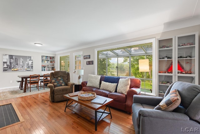 603 Outer Dr, Tecumseh, MI 49286 - living room featuring light wood-style flooring, built in shelves, and a sunroom