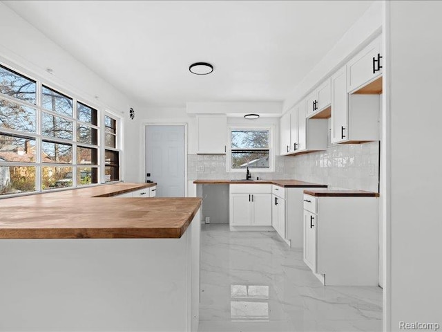 19468 Evergreen Rd, Detroit, MI 48219 - kitchen featuring light marble finish floors, a sink, backsplash, wood counters, and a peninsula