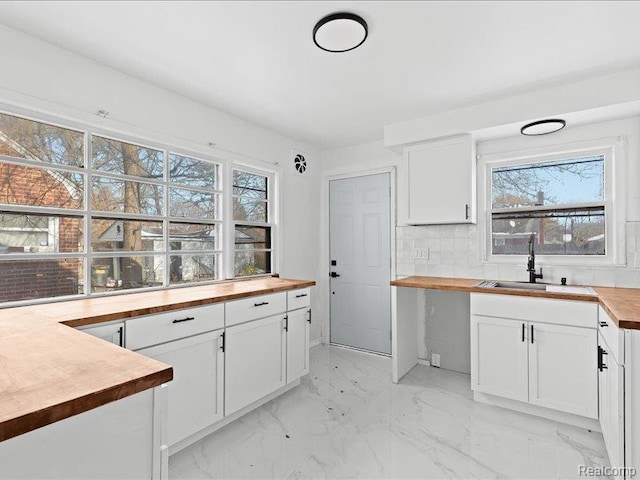 19468 Evergreen Rd, Detroit, MI 48219 - kitchen with butcher block counters, a sink, white cabinetry, light marble finish floors, and decorative backsplash