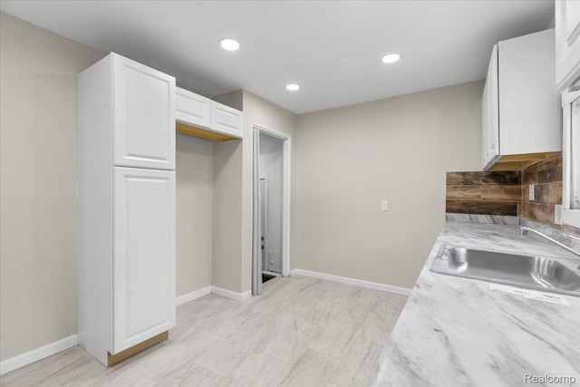 9207 Stout St, Detroit, MI 48228 - kitchen with a sink, white cabinets, baseboards, recessed lighting, and light stone counters
