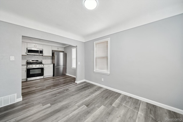 5932 Colorado St, Romulus, MI 48174 - kitchen with appliances with stainless steel finishes, baseboards, wood finished floors, light countertops, and white cabinets