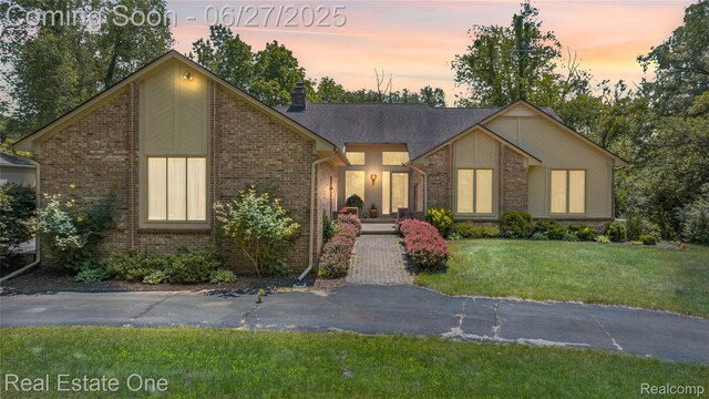 1145 W Moore Rd, Milford, MI 48381 - mid-century home featuring brick siding, a front yard, and a chimney