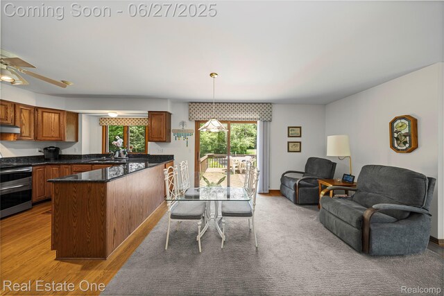1145 W Moore Rd, Milford, MI 48381 - kitchen featuring range with two ovens, open floor plan, brown cabinetry, light wood finished floors, and decorative light fixtures