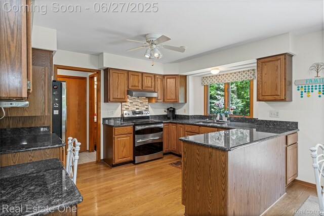 1145 W Moore Rd, Milford, MI 48381 - kitchen with double oven range, under cabinet range hood, a ceiling fan, a peninsula, and dark stone countertops