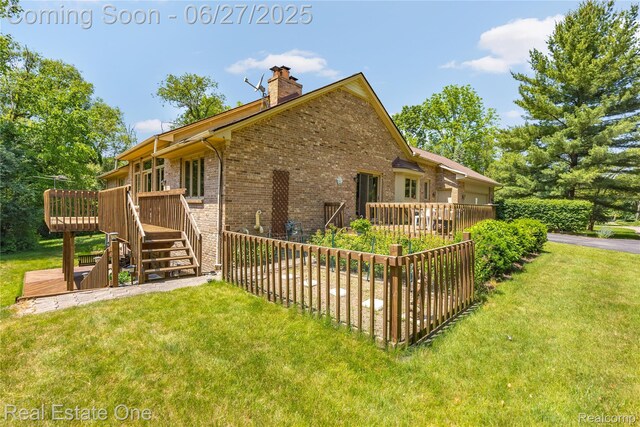 1145 W Moore Rd, Milford, MI 48381 - rear view of property with a deck, brick siding, a lawn, a chimney, and stairs