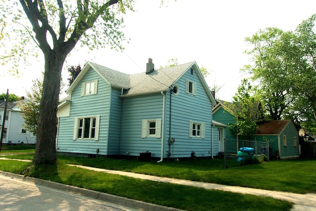 602 Fairview Ave, Manistee, MI 49660 - view of side of home featuring a chimney, a lawn, and a shingled roof