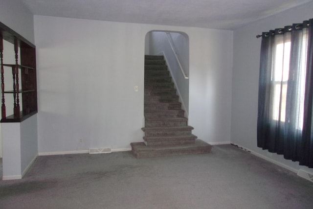 602 Fairview Ave, Manistee, MI 49660 - carpeted spare room with arched walkways, baseboards, and stairway