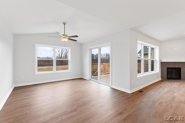 2819 Eunice Cir, Adrian, MI 49221 - unfurnished living room featuring a ceiling fan, wood finished floors, a tiled fireplace, baseboards, and lofted ceiling