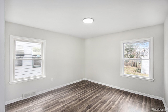 20265 Yonka St, Detroit, MI 48234 - empty room with dark wood-type flooring, plenty of natural light, and baseboards