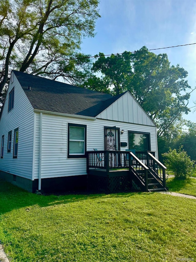 2825 Raskob St, Flint, MI 48504 - view of front facade featuring board and batten siding, a front lawn, and roof with shingles