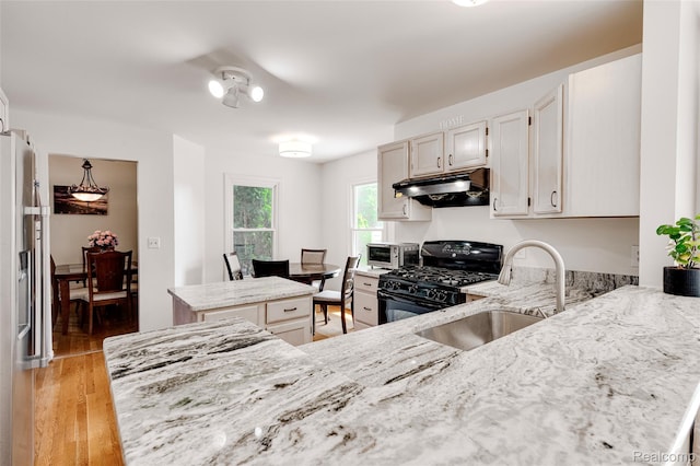 39719 Squire Rd, Novi, MI 48375 - kitchen with black range with gas stovetop, under cabinet range hood, a sink, light stone counters, and a kitchen island