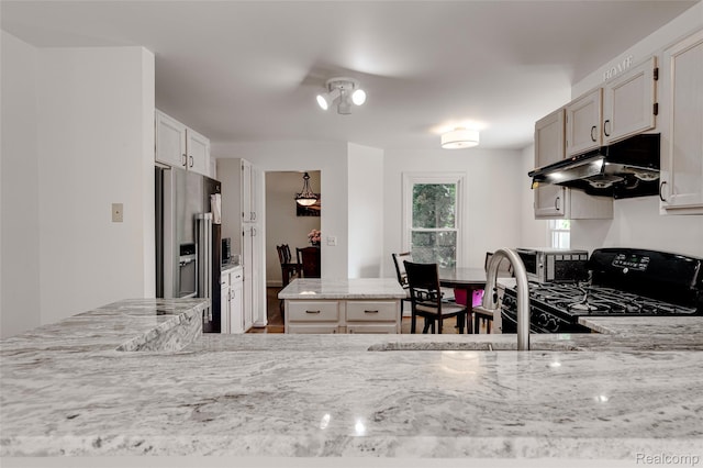 39719 Squire Rd, Novi, MI 48375 - kitchen with stainless steel refrigerator with ice dispenser, under cabinet range hood, black range oven, light stone countertops, and a sink