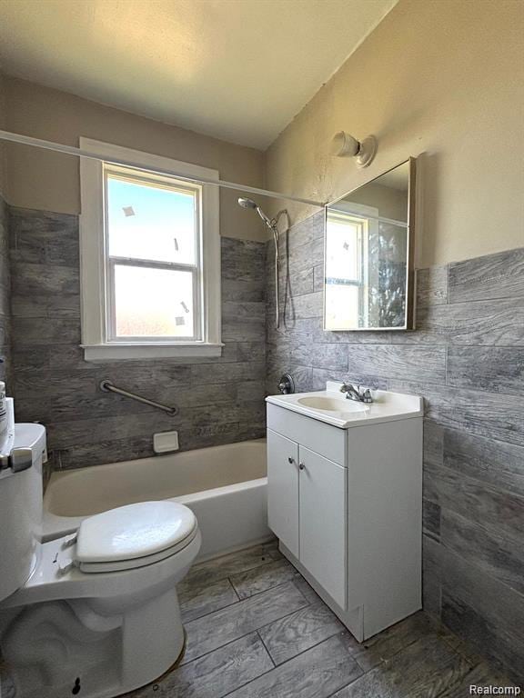 2340 Clements St, Detroit, MI 48238 - bathroom featuring vanity, toilet, tub / shower combination, and tile walls