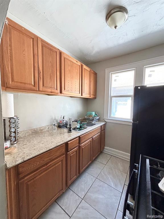 2340 Clements St, Detroit, MI 48238 - kitchen featuring a sink, light tile patterned floors, brown cabinetry, and range