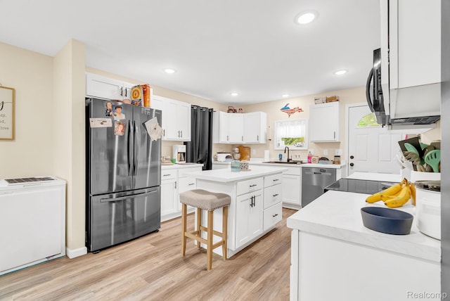 5668 Mill St, Peck, MI 48466 - kitchen featuring appliances with stainless steel finishes, white cabinetry, a center island, light wood finished floors, and a breakfast bar