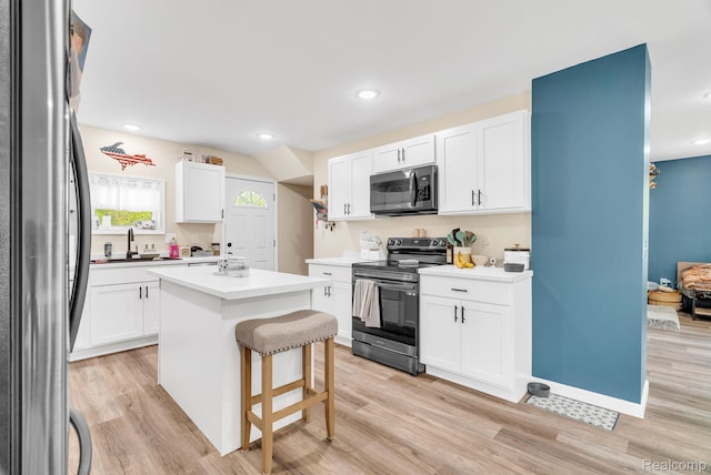 5668 Mill St, Peck, MI 48466 - kitchen with appliances with stainless steel finishes, white cabinetry, light wood-style flooring, a center island, and a kitchen breakfast bar