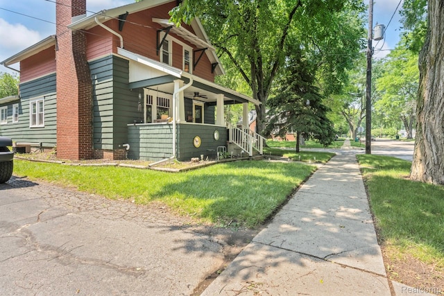 819 N Ball St, Owosso, MI 48867 - view of home's exterior featuring a chimney, a porch, and a yard