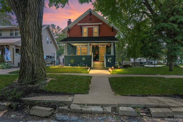 819 N Ball St, Owosso, MI 48867 - view of front of home with covered porch, a lawn, and a chimney