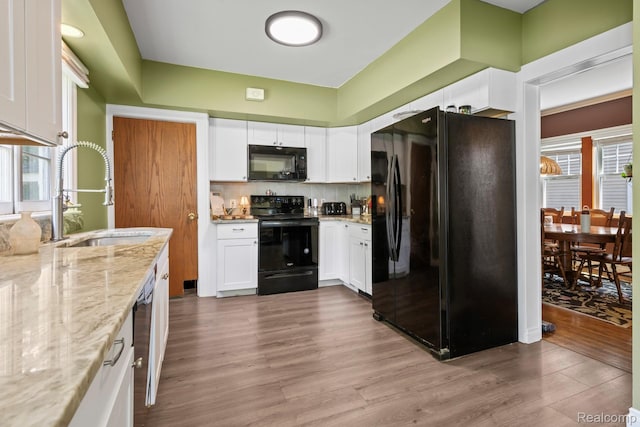 819 N Ball St, Owosso, MI 48867 - kitchen with black appliances, a sink, light stone countertops, white cabinetry, and wood finished floors
