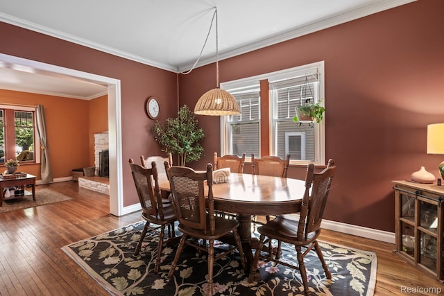 819 N Ball St, Owosso, MI 48867 - dining area with hardwood / wood-style flooring, ornamental molding, baseboards, and a stone fireplace