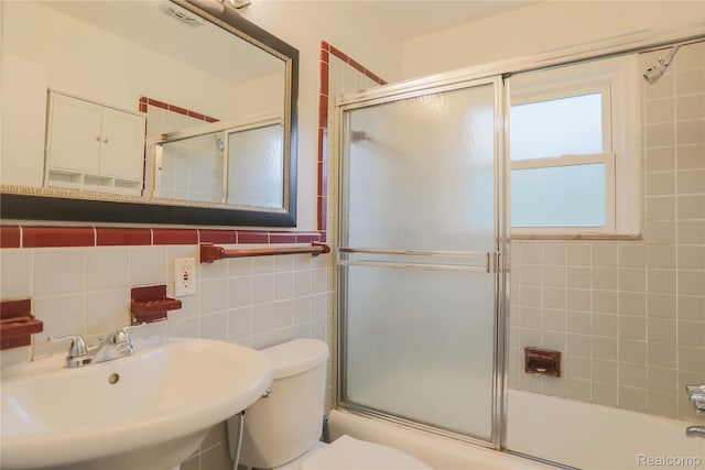 3581 Stolzenfeld Ave, Warren, MI 48091 - bathroom featuring a sink, toilet, bath / shower combo with glass door, and tile walls