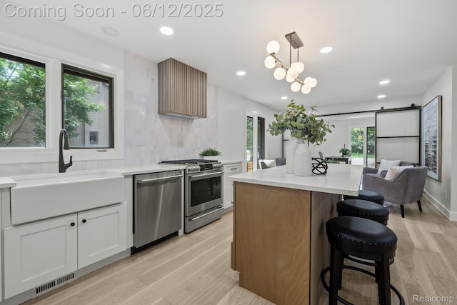 3405 Pine Estates Dr, Bloomfield Hills, MI 48323 - kitchen featuring stainless steel appliances, light wood-type flooring, a kitchen breakfast bar, decorative light fixtures, and a center island